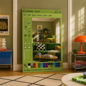 Può includere: Un grande specchio con cornice verde progettato per assomigliare a una finestra di Paint di Windows. Lo specchio riflette un soggiorno con un divano verde, opere d'arte e una lampada arancione. Il testo "untitled - Paint" è visibile in alto.