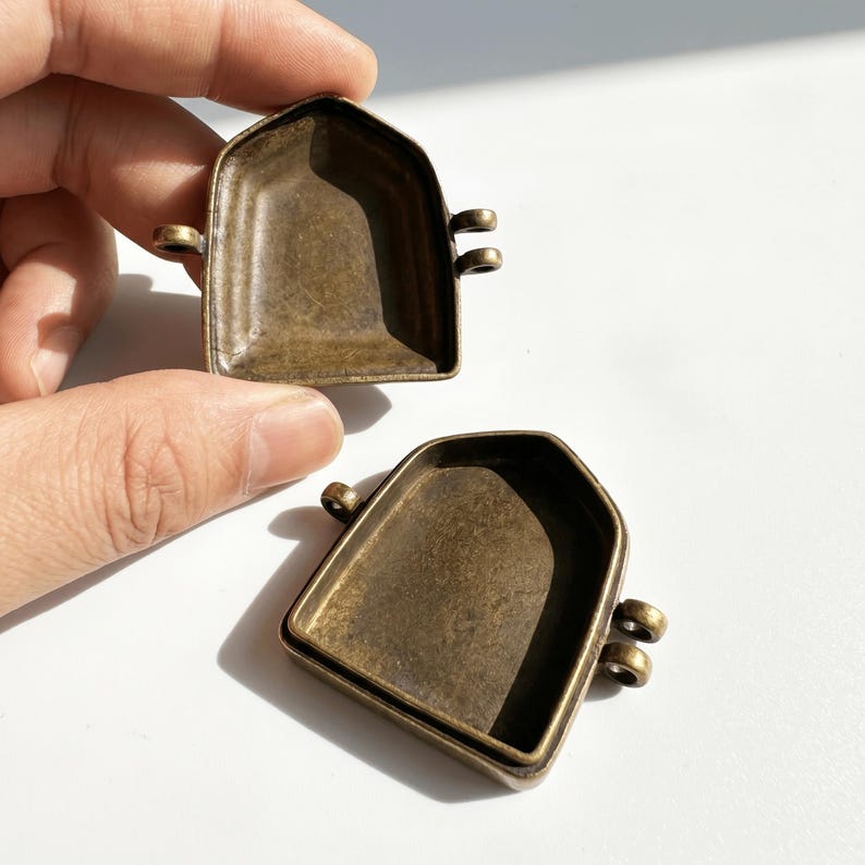 K&ouml;nnte beinhalten: Zwei anh&auml;ngerf&ouml;rmige Metallschalen in antikem Messingfarbton mit spitzer Bogenform. Jede Schale verf&uuml;gt &uuml;ber eine vertiefte Mitte sowie zwei kleine &Ouml;sen auf einer Seite und eine &Ouml;se auf der gegen&uuml;berliegenden Seite zur Befestigung.