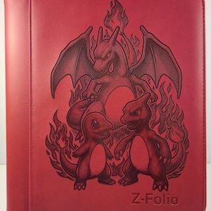 May include: Red Z-Folio binder featuring a detailed illustration of a Charizard and its evolutions, surrounded by flames. The binder has a zipper closure and the text "Z-Folio" embossed on the front.