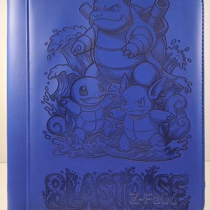 May include: Blue binder featuring a detailed embossed design of the Pokémon Blastoise and its pre-evolved forms, Squirtle and Wartortle, with water effects. The word "BLASTOISE" is printed at the bottom.
