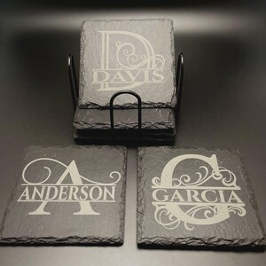 Pode incluir: Um conjunto de bases para copos quadradas em ard&oacute;sia com bordas naturais e rugosas. Cada base apresenta uma letra de monograma gravada a laser com ornamentos decorativos e um apelido, incluindo Davis, Anderson e Garcia.
