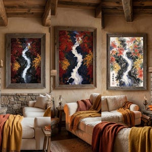 May include: Three framed wall art prints displayed above a sofa, each depicting a winding waterfall surrounded by vibrant red and yellow autumn foliage. The artwork features a vertical composition with dark rocks and flowing white water.