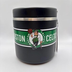 Puede incluir: Vaso térmico negro con una banda plateada y una tapa negra. El vaso presenta una banda verde y blanca con las palabras "BOSTON CELTICS" y un logotipo de un duende sosteniendo una pelota de baloncesto.