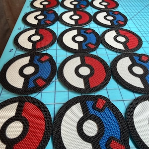 May include: A collection of circular embroidered patches arranged in rows. Each patch features a stylized sphere design divided into two halves with a central circle, rendered in combinations of red, white, and blue thread with black borders.