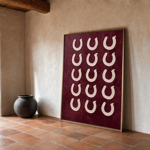May include: A rectangular framed wall art piece featuring a deep burgundy textured background with fifteen white, U-shaped brushstroke motifs arranged in a grid of three columns and five rows, enclosed in a thin, metallic gold-toned frame.
