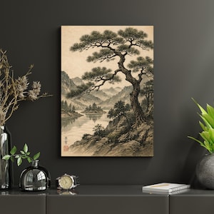 May include: A framed landscape art print depicting a serene Asian-inspired scene. The artwork features a large, detailed tree in the foreground, with a lake and mountains in the background. The color palette is primarily muted earth tones, creating a calming aesthetic.