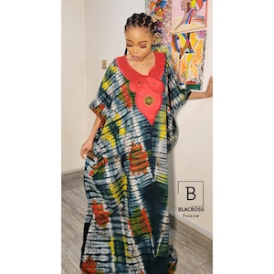 May include: A tie-dye patterned dress with a red neckline and a decorative red accent. The dress features a loose, flowing design with short sleeves. The Blacboss Fashion logo is visible in the lower right corner.