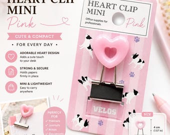 May include: A pink heart-shaped binder clip on a pink and white striped backing card featuring French bulldog illustrations. The clip has a pink heart top and a black metal base with the text VELOS. A diagram shows a height of 1.57 inches.