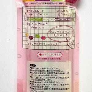 May include: A pink plastic packaging containing a set of four 0.5mm Pilot Juice gel pens. The packaging features Japanese text, illustrations of gummy candies, and a barcode at the bottom. The pens are visible through the clear window section.