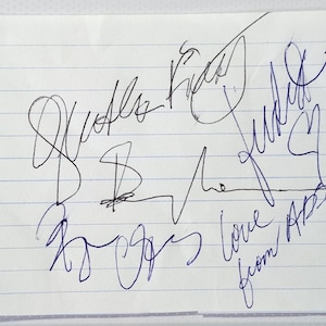 May include: A sheet of lined paper with several signatures in blue ink. The paper has a torn edge on the left. The signatures are in cursive and include the words "love" and "from".