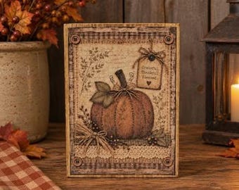 May include: A rectangular wooden sign featuring a central illustration of a pumpkin with green leaves, surrounded by botanical sketches. A small tag attached with twine reads Grateful Thankful Blessed. The border has a plaid pattern and four buttons.