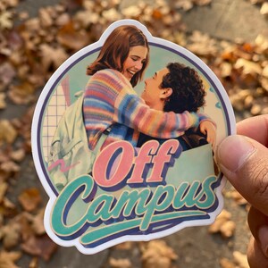 May include: A sticker featuring a couple embracing, with the words "Off Campus" in a retro font. The woman wears a colorful striped sweater. The sticker has a white border and a vintage aesthetic.