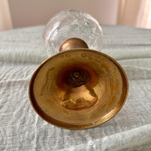 May include: A vintage glass vase with a crackle finish, featuring a brass base and stem. The vase has a bulbous shape and a clear, textured appearance. The brass components show signs of age and wear.