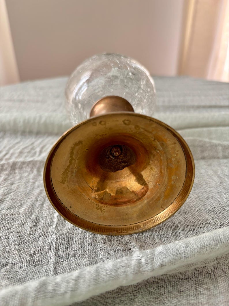 May include: A vintage glass vase with a crackle finish, featuring a brass base and stem. The vase has a bulbous shape and a clear, textured appearance. The brass components show signs of age and wear.