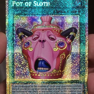 May include: A holographic trading card titled Pot of Sloth, featuring a pink, pot-shaped creature with a wide-open mouth, blue tongue, and dark horns. The card includes text describing game mechanics and has a shimmering, rainbow-colored foil finish.