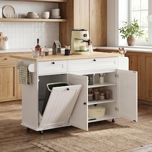 May include: A white kitchen island with a light wood countertop, featuring a built-in trash can, storage cabinets, and drawers. A coffee maker and various kitchen items are on the countertop. The island is on wheels and has a neutral color scheme.