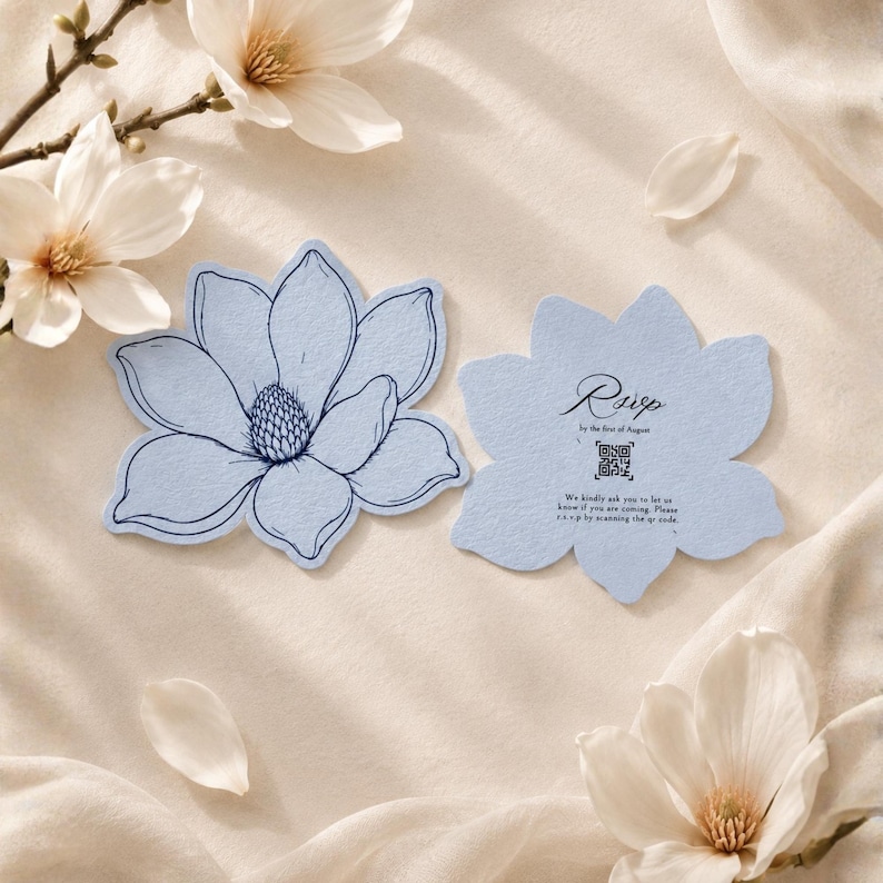 May include: Two light blue, flower-shaped cards with dark blue ink. One card features a detailed line drawing of a magnolia blossom. The other card displays the text RSVP by the first of August, a QR code, and instructions to scan the code.