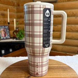 Pode incluir: Uma caneca de viagem HydroJug xadrez branca e marrom com uma al&ccedil;a grande. A caneca tem uma base de borracha e &eacute; &agrave; prova de vazamentos. Mant&eacute;m a &aacute;gua fria por at&eacute; 24 horas e n&atilde;o cont&eacute;m BPA. A caneca pode ser lavada na m&aacute;quina de lavar lou&ccedil;a e cont&eacute;m cerca de 1,14 litros.