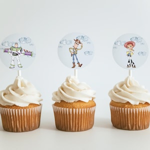 May include: Three cupcakes with white icing, each topped with a circular image of a Toy Story character: Buzz Lightyear, Woody, and Jessie. The cupcakes are on a white surface, ideal for a themed party.