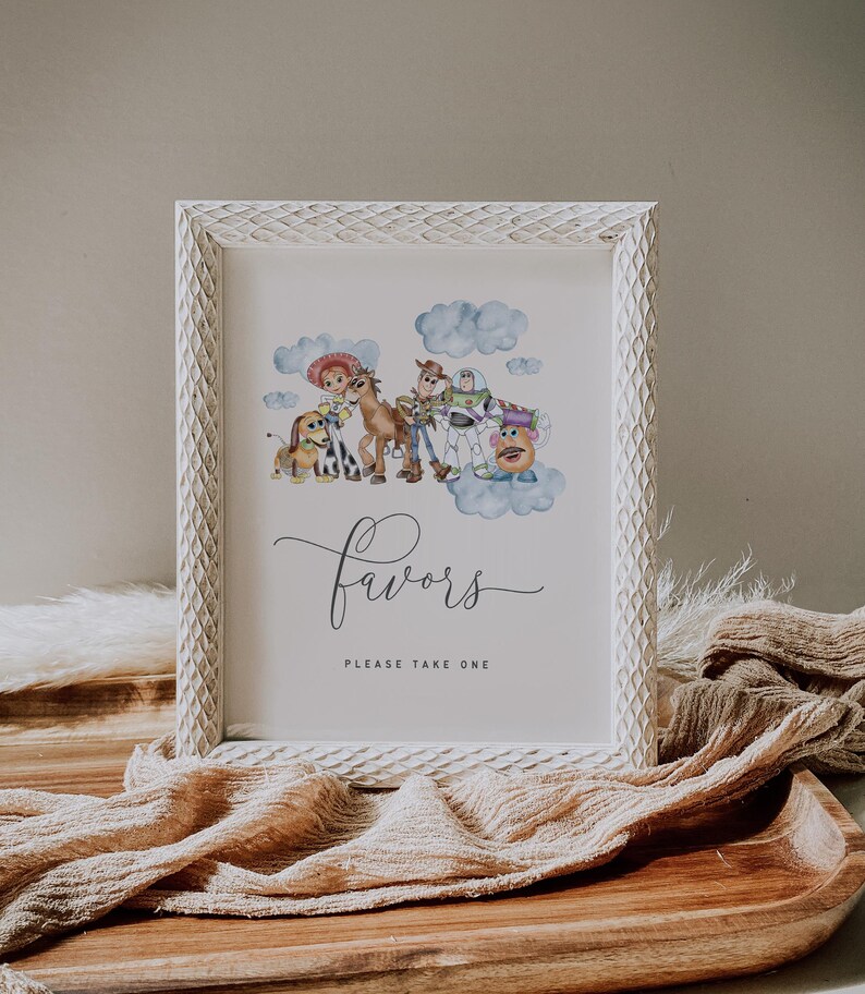May include: White framed print with watercolour illustrations of animated film characters. The print includes the word "Favors" in cursive script, with the text "PLEASE TAKE ONE" below. The frame has a textured, carved design.