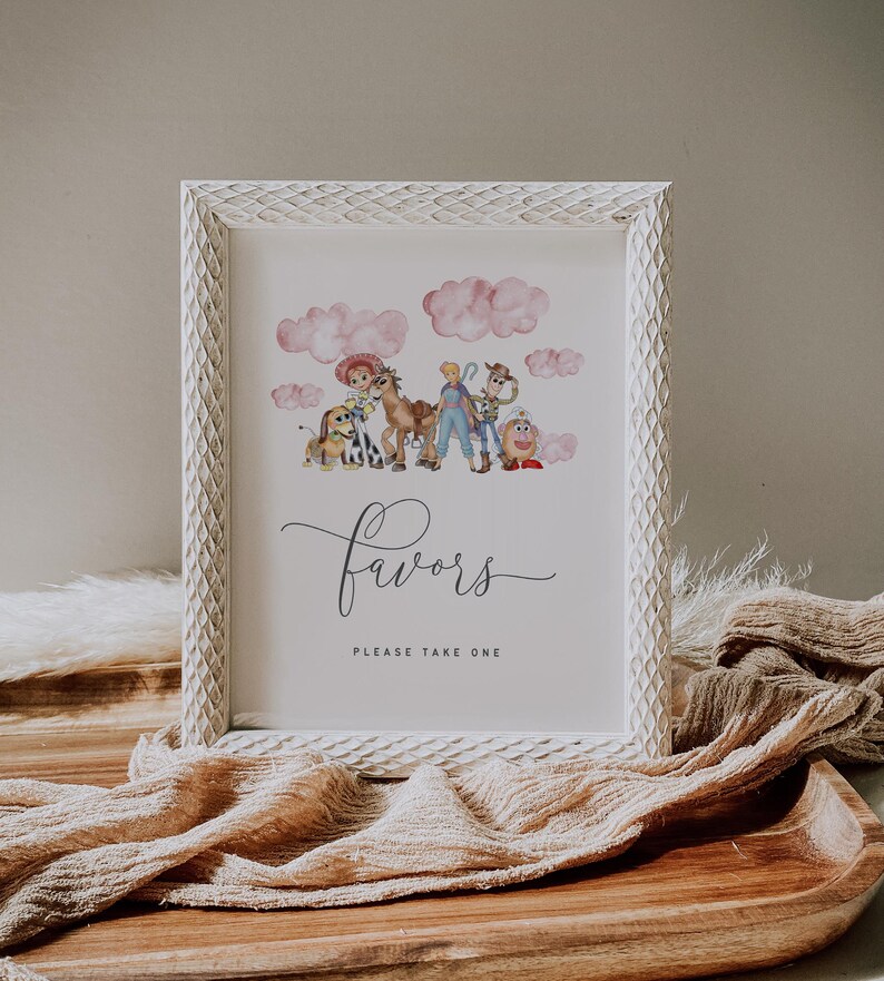 May include: White framed print with watercolor illustrations of cartoon characters and pink clouds. The word "favors" is written in cursive, with "PLEASE TAKE ONE" below. The frame has a textured, carved design.