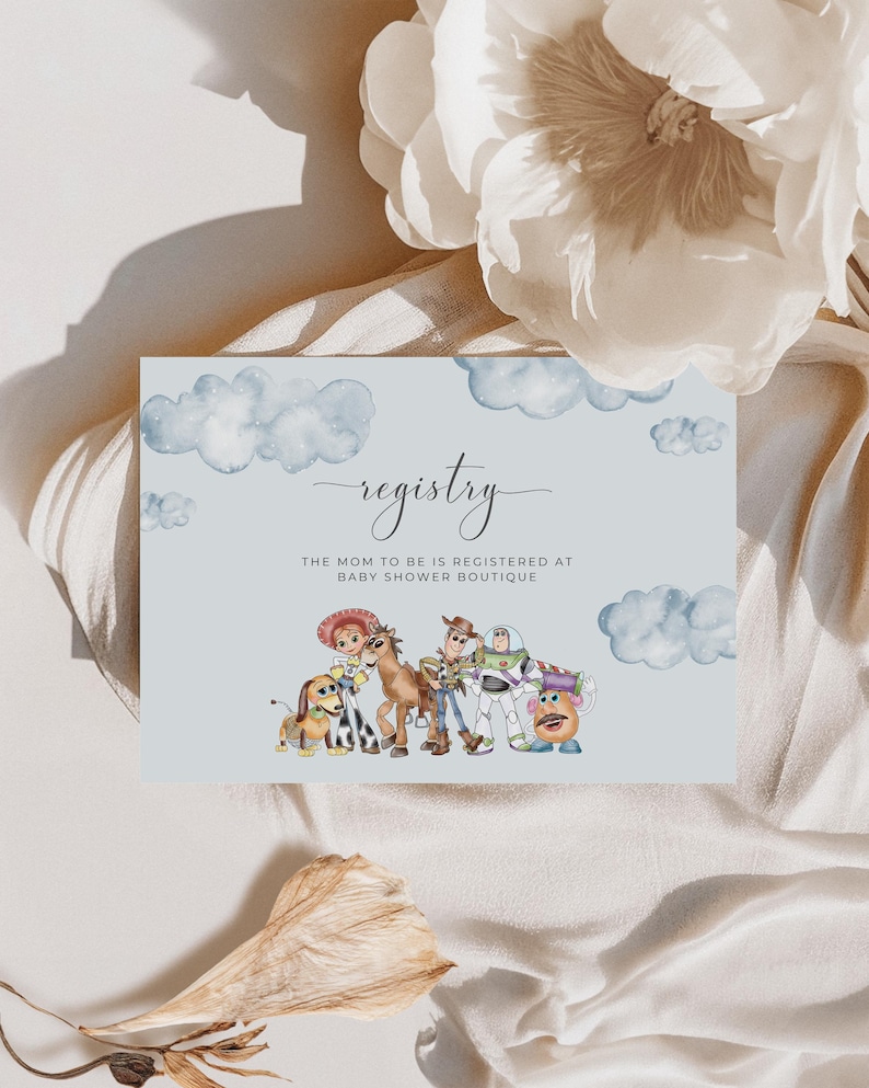 May include: A pale blue baby shower registry card featuring watercolour clouds and Toy Story characters. The card says "registry" in elegant script, with the text "The mom to be is registered at Baby Shower Boutique" beneath.