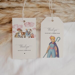 May include: Two cream-colored gift tags with string. One tag features a watercolor illustration of characters from a movie, with the text "Thank you, You've got a friend in me." The other tag shows a character with a staff and the same text.