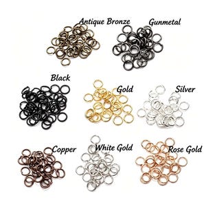Peut inclure: Huit tas distincts d'anneaux de jonction en métal étiquetés Antique Bronze, Gunmetal, Black, Gold, Silver, Copper, White Gold et Rose Gold. Chaque tas contient de nombreux petits anneaux métalliques circulaires ouverts pour la bijouterie.