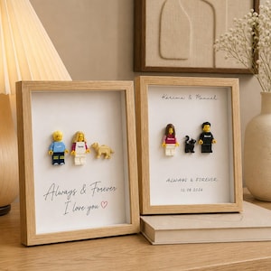 May include: Two light wood shadow box frames containing custom plastic minifigures and pets. The left frame displays two figures and a dog with the text Always & Forever I love you. The right frame shows two figures and a cat with names and a date.