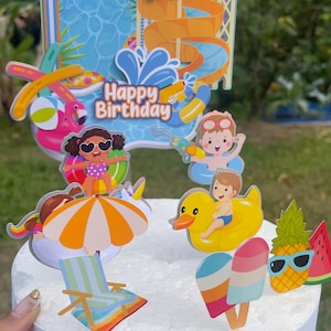 May include: A multi-piece cake topper set featuring a pool party theme with a large arch, a yellow sun, and the text "Pool Party" and "Happy Birthday". Includes illustrations of children in pool floats, a beach umbrella, a lounge chair, and ice lollies.