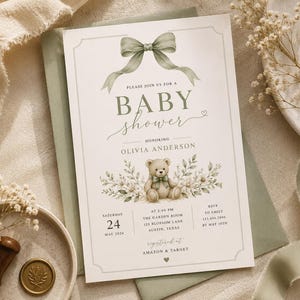 Può includere: Invito per baby shower con illustrazione di orsetto, dettagli floreali e un fiocco verde salvia. L'invito include i dettagli per il baby shower di Olivia Anderson, con data, ora e luogo. Registrato su Amazon & Target.