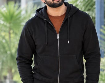 May include: A black zip-up hoodie featuring a drawstring hood, long sleeves with ribbed cuffs, and a front kangaroo pocket. The hoodie is worn over a solid brown t-shirt, with matching black pants visible at the waistline.