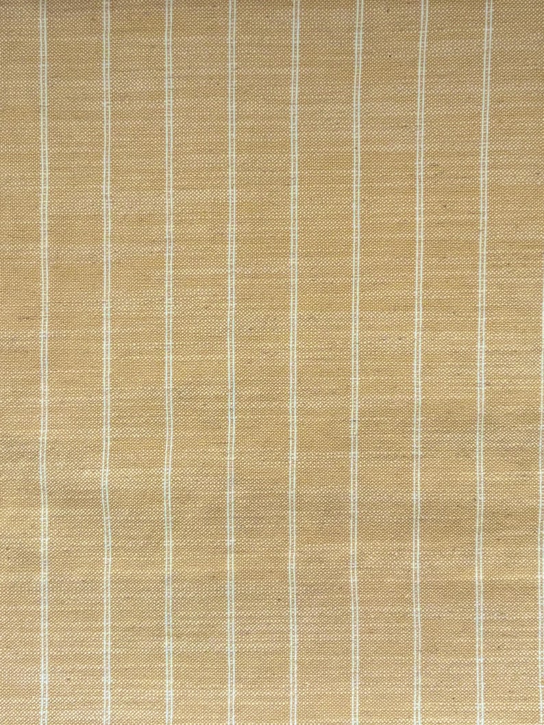 May include: Tan fabric with vertical white stripes. The fabric has a woven texture, and the stripes are evenly spaced. The overall appearance is neutral and suitable for various design applications, such as upholstery or drapery.