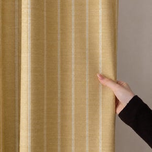 May include: Yellow and white striped fabric, likely a curtain or drapery. The fabric has vertical stripes of yellow and white. The texture appears to be woven. The image shows a section of the fabric being held.