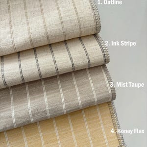 May include: Four stacked fabric swatches with vertical stripes. 1. Oatline is a light beige with thin brown stripes. 2. Ink Stripe is a light beige with thin black stripes. 3. Mist Taupe is a medium beige with white stripes. 4. Honey Flax is a golden yellow with white stripes.