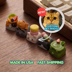 May include: A collection of colorful, decorative keycaps with food-themed designs, including a fish, a macaron, and a cake. A "NEW!" sticker and a custom pet photo are also visible. The text "MADE IN USA" is at the bottom.