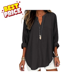 May include: A dark charcoal grey long-sleeve shirt with a split V-neckline and rolled cuffs. The shirt features a textured fabric finish and is paired with white shorts. A long silver-toned necklace with a pendant hangs down the centre front.