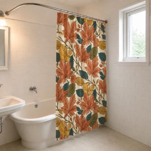 May include: A shower curtain featuring a repeating pattern of autumn leaves in shades of orange, yellow, and dark teal against a cream-colored background. The design includes detailed leaf veins and stems, hanging from a curved metal shower rod.
