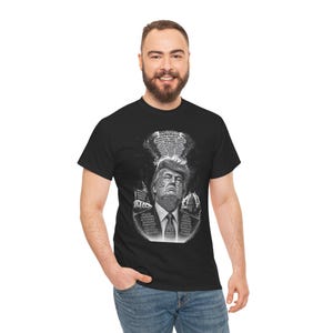Può includere: Una t-shirt nera con una stampa grafica monocromatica di Donald Trump. Il design include il testo NARCISSIST e EGOMANIACAL in alto, con varie parole descrittive sovrapposte al ritratto e all'abito, tra cui PITILESS e VILLAINOUS.