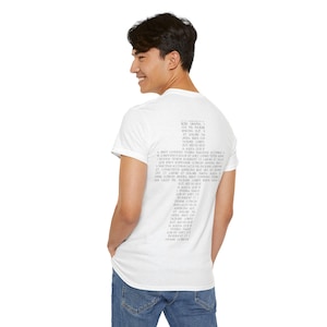 Può includere: T-shirt bianca con girocollo e maniche corte. La parte posteriore della maglietta presenta una colonna verticale di testo in grigio chiaro. Il testo sembra essere un elenco di parole o frasi. La persona indossa jeans blu.