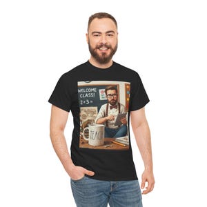 Può includere: Una t-shirt nera con una stampa grafica di un insegnante barbuto con occhiali, papillon e bretelle, che tiene in mano un tablet. La grafica include una lavagna con il testo "WELCOME CLASS! 2+3=" e una tazza bianca con il testo "TEACH".