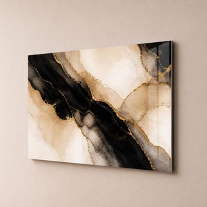 Könnte beinhalten: Abstrakter Kunstdruck mit einer Farbpalette aus Schwarz, Beige und Gold. Das Kunstwerk hat einen Aquarelleffekt mit goldenen Akzenten, die die Formen umreißen. Das Stück ist an einer Wand montiert und zeigt eine moderne Ästhetik.