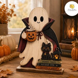 May include: A wooden ghost figurine wearing a black cape with a dark red lining, holding an orange jack-o'-lantern mug. A black cat sits on a stack of three books titled Spooky Tales, Wicked Fun, and Potions & Brews next to a small lantern.