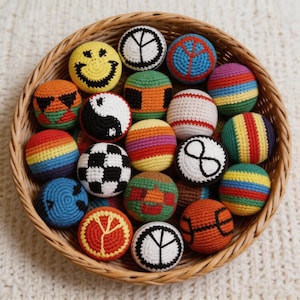 May include: A collection of colorful, crocheted balls with various designs, including a smiley face, peace signs, and rainbow stripes, are displayed in a woven basket. The balls are in various colors, such as yellow, black, red, blue, and green.