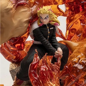 May include: A detailed anime-style figurine of a character with spiky blonde hair and red highlights, wearing a black uniform with gold buttons. The figure is surrounded by translucent, orange and red flame-like effects and holds a sword.