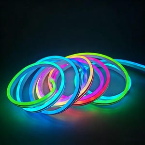 May include: A coiled, flexible LED neon light strip in a variety of colors, including green, blue, pink, and red. The strip is illuminated, creating a vibrant and colorful display against a dark background. The light strip is ideal for decorative lighting.