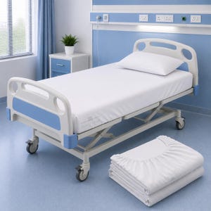 May include: A hospital bed with a white mattress and a single white pillow, featuring light blue accents on the headboard and footboard. A folded white fitted sheet is placed on the floor in the foreground, matching the bedding on the bed frame.