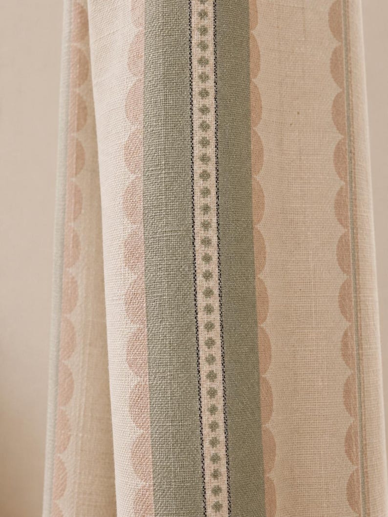 May include: A woven fabric featuring vertical stripes in sage green and beige. The pattern includes a central band with a small repeating diamond motif, flanked by wider sage green stripes and scalloped edges in a soft peach tone on a beige base.