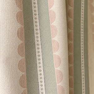 May include: A woven fabric featuring vertical stripes in sage green and soft peach. The pattern includes rows of scalloped semi-circles in peach alongside solid sage green bands and a narrow white stripe with a repeating small diamond motif.