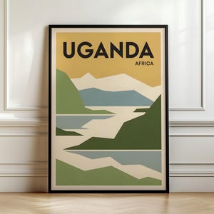 May include: A framed wall art print featuring a stylized landscape of Uganda, Africa. The graphic design displays layered mountains and water in shades of green, blue, and cream against a golden yellow sky, with the text UGANDA AFRICA at the top.